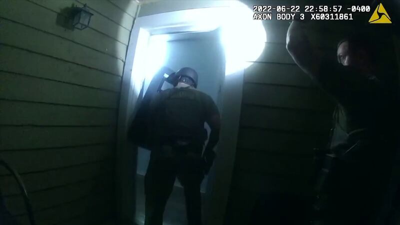 A still image from police body camera video shows an officer in armor holding a shield...